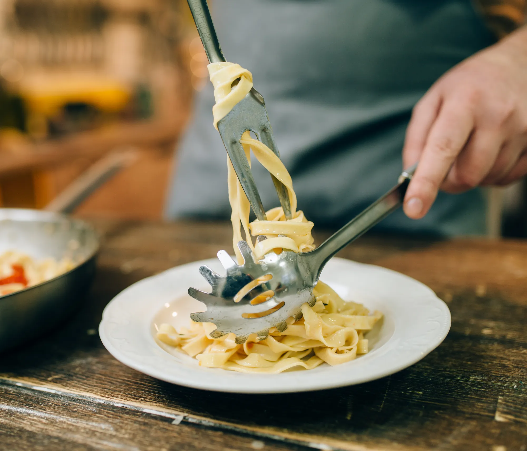 male-chef-puts-fresh-pasta-in-a-plate